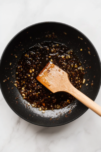 This image shows diced onion and garlic being added to the skillet.