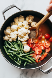 adding-cauliflower-green-beans-tomatoes-beef-broth-worcestershire-sauce-to-the-sauted-vegetables-in-the-crockpot