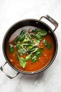 resh spinach leaves being stirred into a pot of simmering soup until the spinach starts to wilt