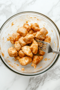 This image shows chopped chicken pieces being added to a bowl of egg mixture.