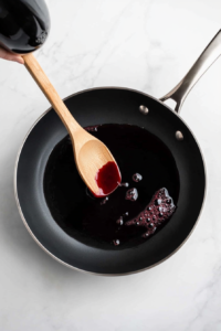 This image shows a pan being deglazed with liquid, scraping up browned bits to create a rich base for the soup.