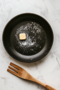 This image shows a skillet heating over medium heat with butter melting in it.