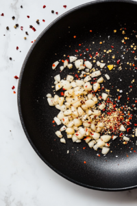 This image shows paprika, garlic granules, and sun-dried tomatoes added to the slow cooker