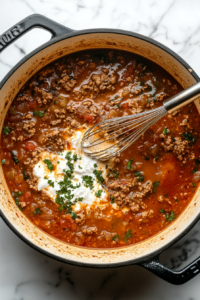 whisking-in-cream-cheese-in-the-broth to make the creamy and cheesy