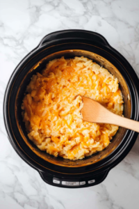 hash-brown-potatoes-and-cheddar-cheese-mixture-being-stirred-in-a-crockpot-again to ensure proper mixing of cheese in hash brown potatoes