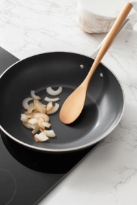 This image shows onions cooking slowly in a skillet, turning soft and dark brown as they caramelize.