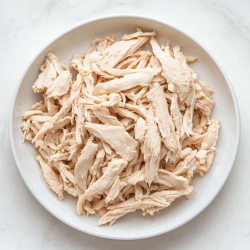 This image shows a top-down view of shredded 2 Ingredient Vegan Chicken presented on a white round plate, ready to enjoy or use in various dishes.