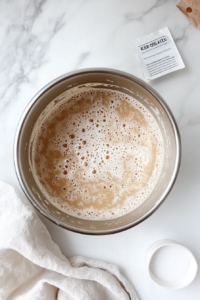 This image shows the yeast mixture foaming and bubbling, indicating it is active and ready for the dough.