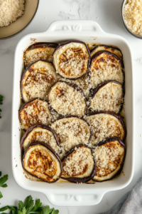 This image shows a second layer of grilled eggplant and savory turkey sauce being added to the lasagna, building up the layers.