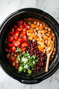 This image shows canned beans and diced tomatoes being poured into the slow cooker, building the rich and hearty base for the chili.