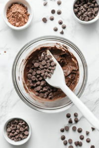 This image shows a handful of chocolate chips being added to the rich brownie batter, giving the vegan pie an extra layer of chocolatey goodness.