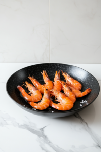 This image shows fresh deveined shrimp being added to the heated skillet to begin cooking for the honey mustard garlic shrimp recipe.