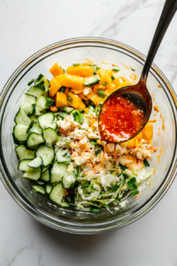 This image shows the prepared dressing being poured over the kani salad ingredients, ready to be mixed and coated with the flavorful dressing.