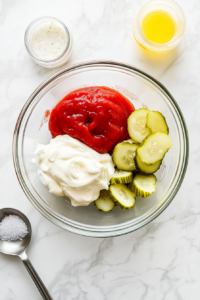 this image shows glass bowl containing mayo, sugar-free ketchup, and freshly squeezed lemon juice, ready to be mixed.