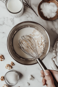 This image shows shredded coconut being stirred into the creamy filling mixture, which is then poured into the baked pie crust for assembling.