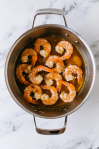 this image shows pot filled with raw shrimp, Old Bay seasoning, and other ingredients ready to be cooked.