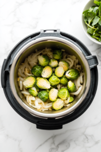 This image shows salt and pepper being added to the Brussels sprouts in the Instant Pot, enhancing the flavor before cooking.