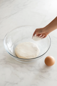 This image shows additional flour being sprinkled over the sticky dough and gently mixed to achieve the right consistency for the no-knead bread.