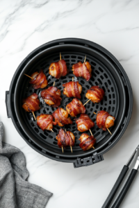 This image shows bacon-wrapped shrimp being neatly arranged in a single layer inside the air fryer basket, ensuring even cooking and crispiness.