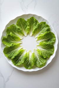 This image shows crisp lettuce leaves being arranged on a plate, ready to be filled with seasoned chicken and toppings for keto-friendly tacos.