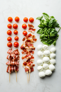 This image shows cocktail skewers being assembled with cherry tomatoes, mozzarella balls, fresh basil leaves, and crispy bacon strips, creating a colorful and flavorful appetizer.