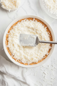 This image shows the pie crust filled with the creamy coconut filling being placed in the oven to bake, ensuring it sets properly.