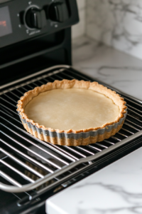 This image shows the crust of the vegan tart baking in the oven, gradually turning golden brown and firm for the rich chocolate filling.