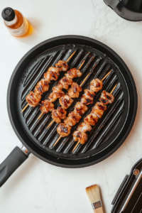 Shrimp skewers being basted with oil during grilling, enhancing their juiciness and flavor.