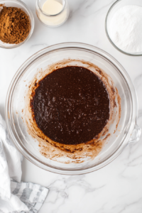 This image shows brownie batter being blended until smooth, combining cocoa powder, dairy-free milk, sugar, and other vegan ingredients for a decadent pie filling.