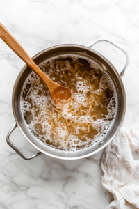 this image shows A large pot filled with boiling water and pasta, being prepared as the base for the Vegan Green Olive Pasta Sauce dish.