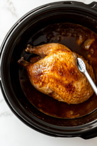 This image shows a meat thermometer being used to check the internal temperature of the turkey breast to ensure it’s fully cooked.