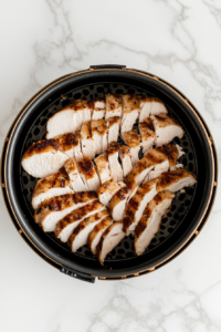 This image shows thin chicken cutlets cooking in the air fryer basket, developing a golden brown and crispy texture on the surface.