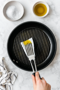 This image illustrates the grill grates being cleaned and lightly greased with olive oil to ensure the skewers do not stick during cooking.