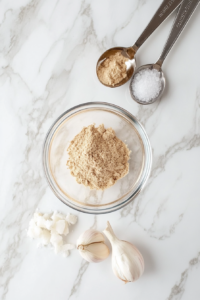 A small white bowl filled with a blend of seasonings, including garlic powder, onion powder, cumin, salt, and pepper, being mixed together with a spoon, ready to coat the chicken for the keto chicken recipe.