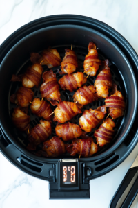 This image shows bacon-wrapped shrimp cooking in the air fryer, achieving a perfectly crispy texture, ideal for a delicious appetizer.