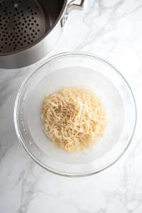 This image shows freshly cooked noodles being drained in a colander, ready to be tossed in the creamy garlic sauce for a delicious and comforting dish.