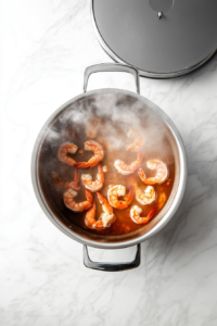 this image shows The pot covered with a lid, allowing the shrimp to cook evenly in the seasoned broth.