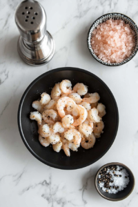 This image shows raw shrimp being cooked in a pan, turning pink and beginning to release their natural juices.