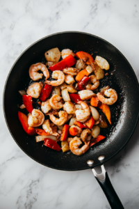 This image shows shrimp being sautéed in melted butter, turning pink and tender, ready to be used as the main filling for the enchiladas.