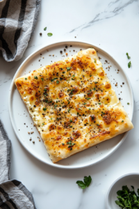 This image shows the freshly baked cottage cheese flatbread cooling on a rack before being served, topped with Italian seasoning for extra flavor.