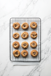 This image shows freshly baked low-calorie chocolate chip cookies resting on a wire rack to cool, with chocolate chips glistening as they melt slightly.