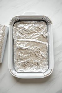 this image shows This image shows the lasagna being covered with foil to keep it moist during the initial baking process.