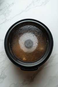 This image shows the slow cooker covered and set to cook, beginning the slow process of blending flavors for the Crockpot Vegetable Soup.