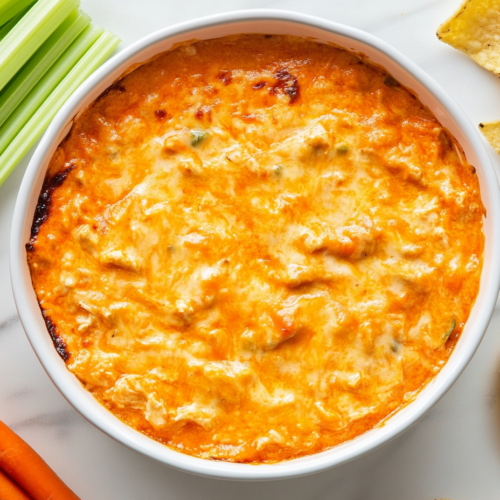 This image shows the Buffalo Chicken Dip cooking in the crockpot, with the cheese melting and the ingredients blending into a creamy and flavorful mixture.