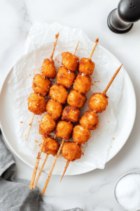 This image displays freshly fried tofu nuggets being placed on a paper towel-lined plate, allowing any excess oil to drain for a light and crispy finish.