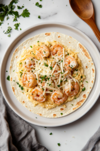 This image shows a tortilla being generously filled with the creamy shrimp mixture, ready to be rolled for assembling the enchiladas.