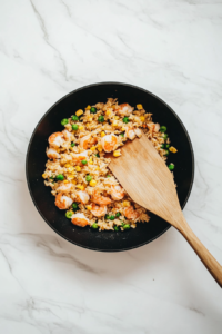 This image shows the final cooking stage of shrimp fried rice, with all ingredients thoroughly combined and heated to perfection, ready to be served.