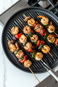 This image illustrates the shrimp skewers being brushed with more lemon butter sauce while on the grill to maximize flavor and moisture.