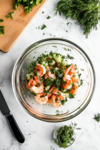 This image shows fresh herbs being added to the jar of pickled shrimp, enhancing the aroma and taste before serving.