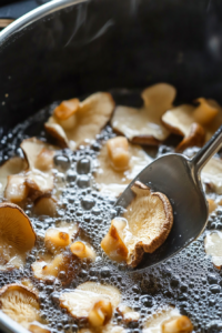 this image shows Coated oyster mushrooms frying in hot vegetable oil, turning golden brown and crispy on each side for the vegan fried chicken recipe.